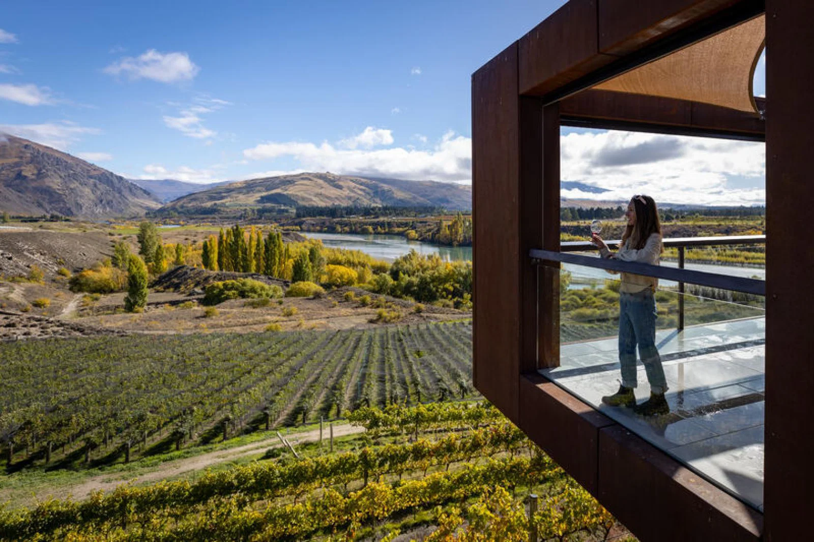 Woman sips on wine while looking over vineyard