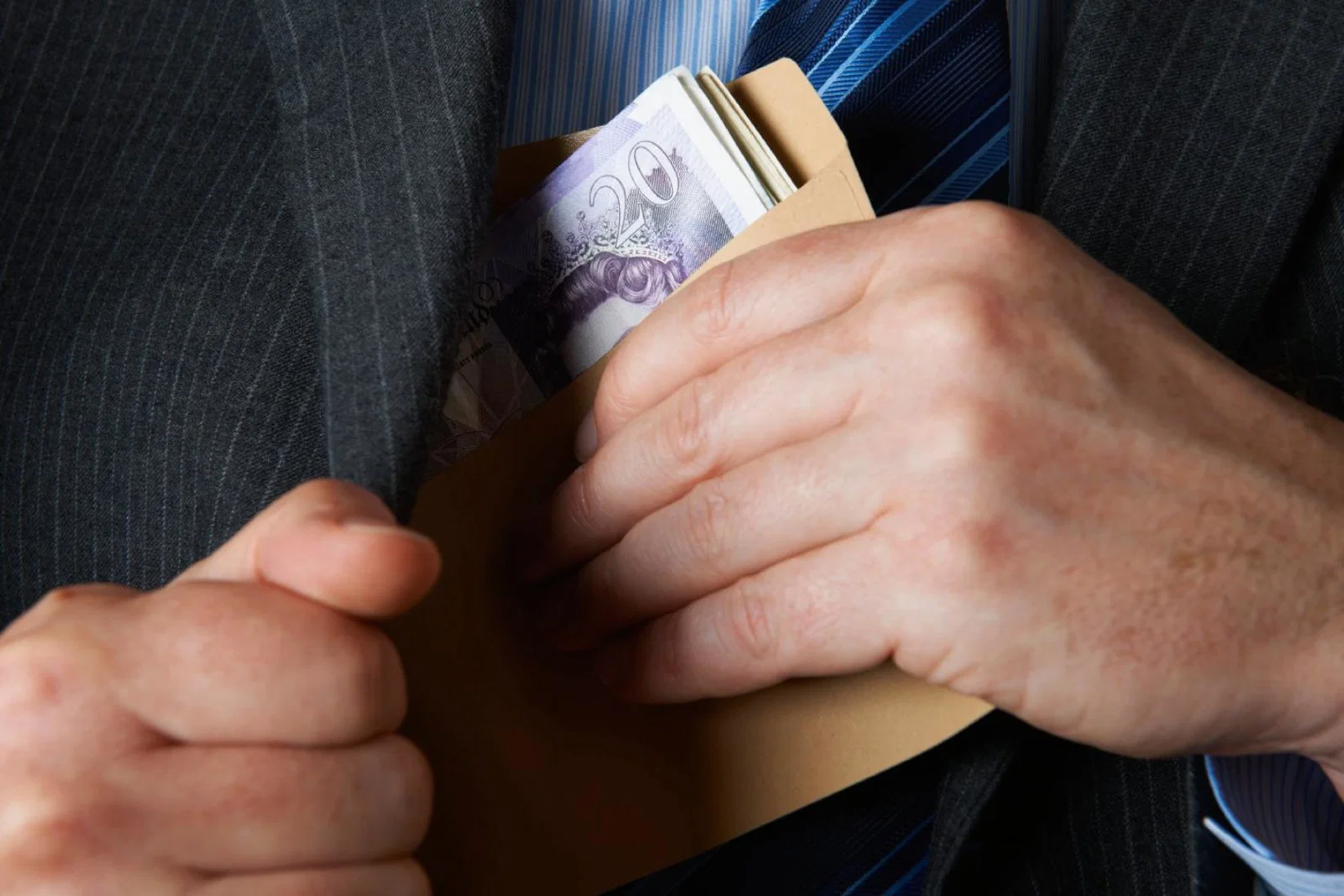 A man places a roll of bank notes in his jacket pocket