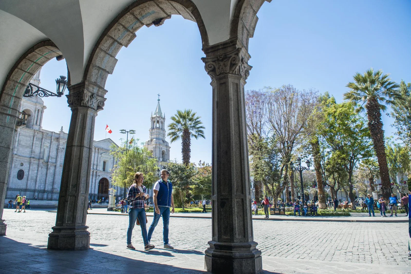 Two people walk through historic central square of Arequipa