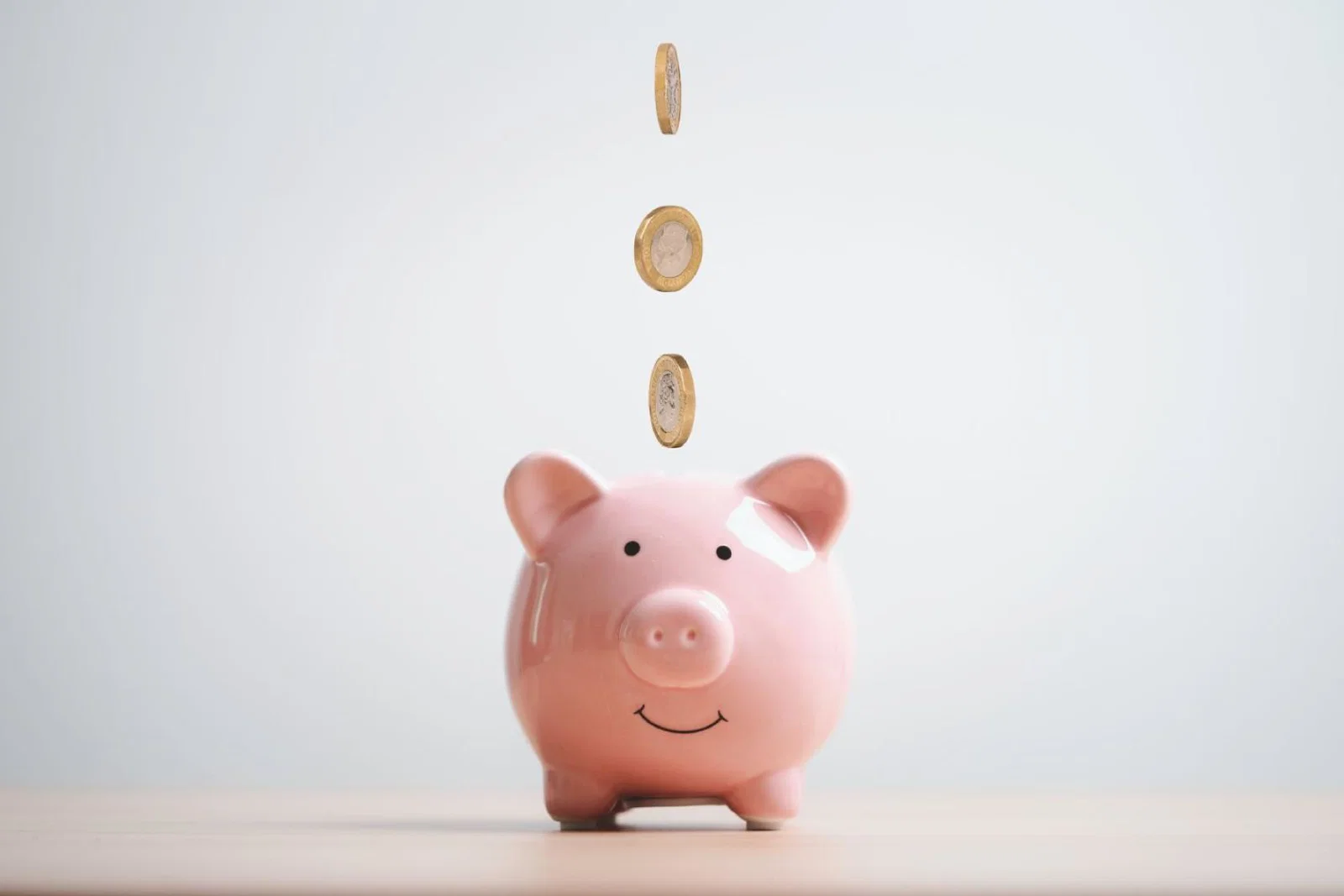Coins falling into a piggy bank