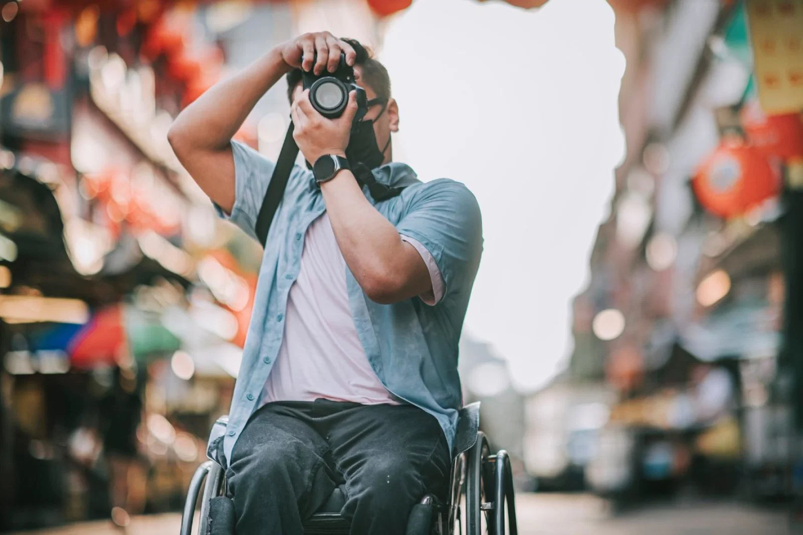 A wheelchair user takes a picture while travelling in an Asian city