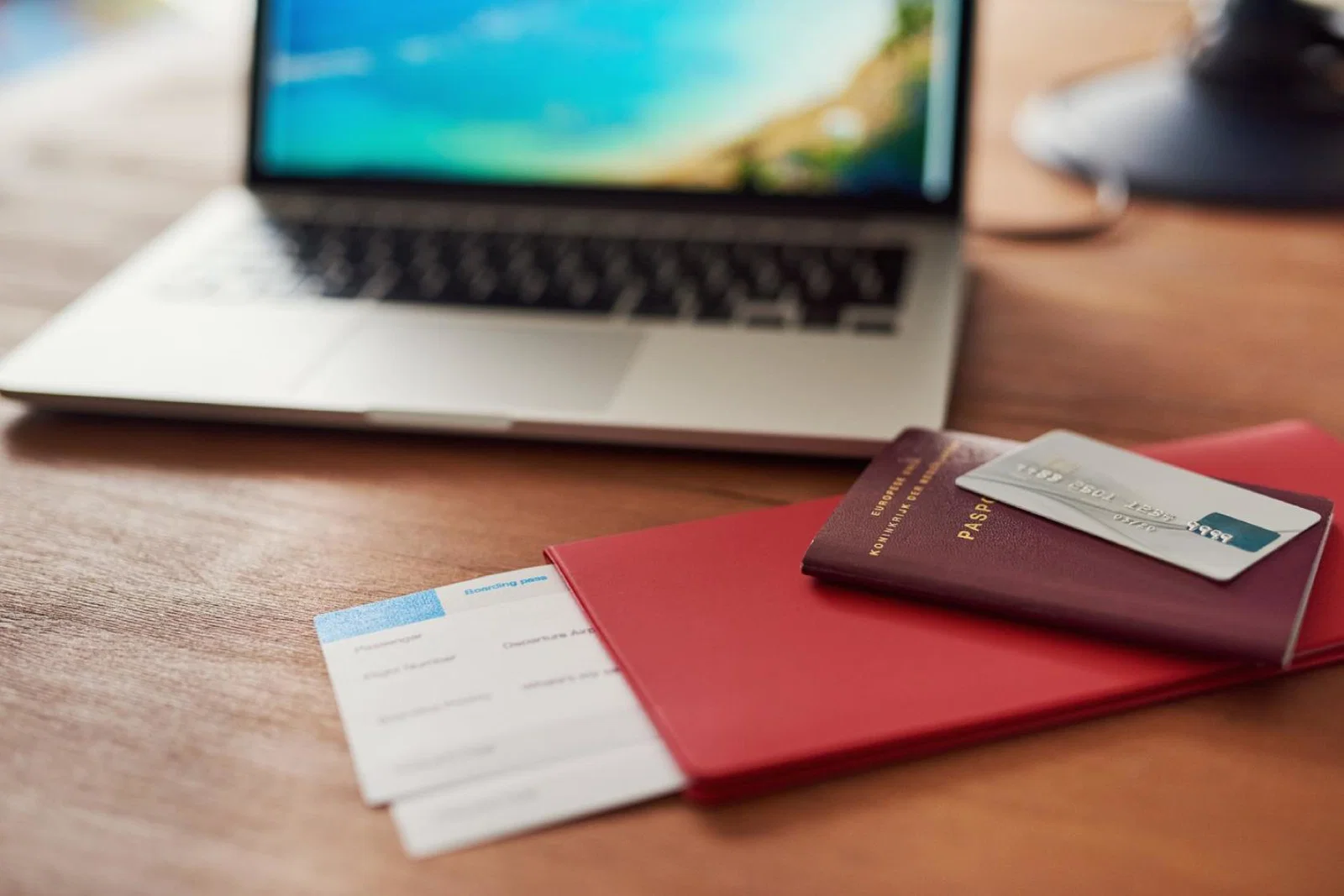 A passport, boarding card and bank card pictured with a laptop in the background
