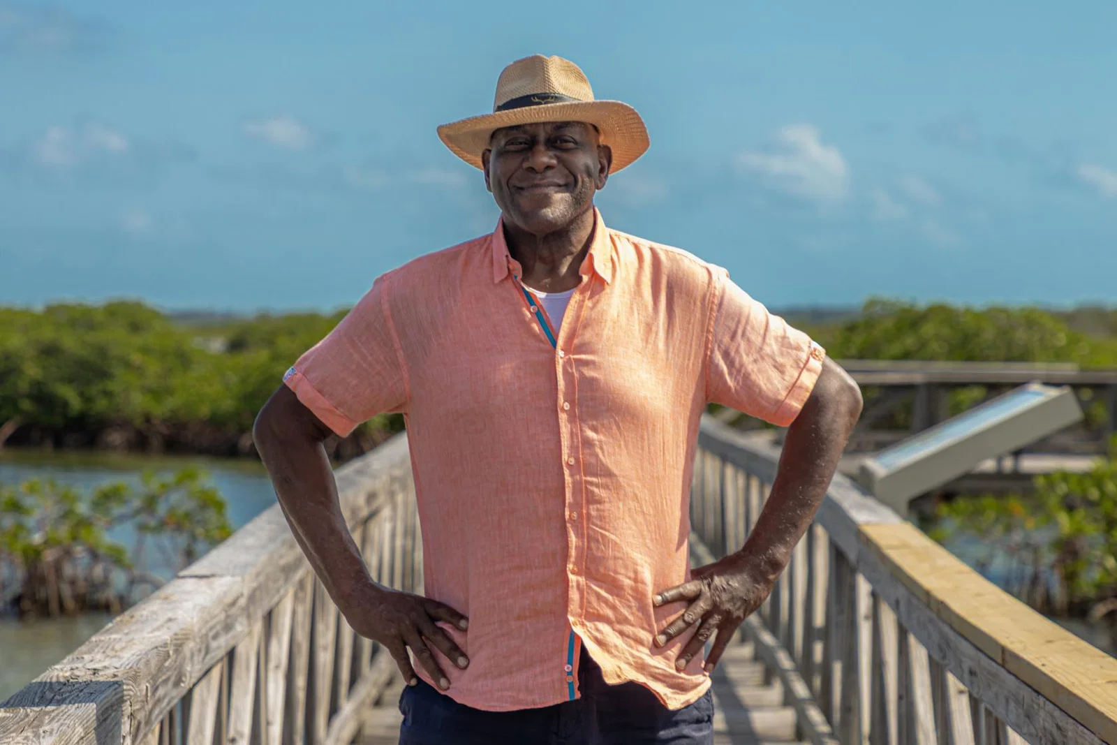 Ainsley Harriot standing with hands on hips on boardwalk over mangrove