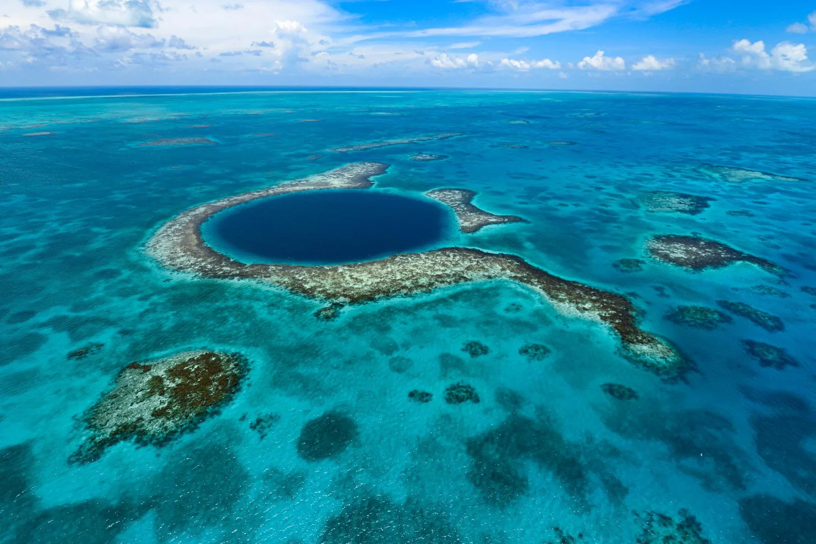 View of Belize Blue Hole from above, a dark blue circle in the middle of clear ocean