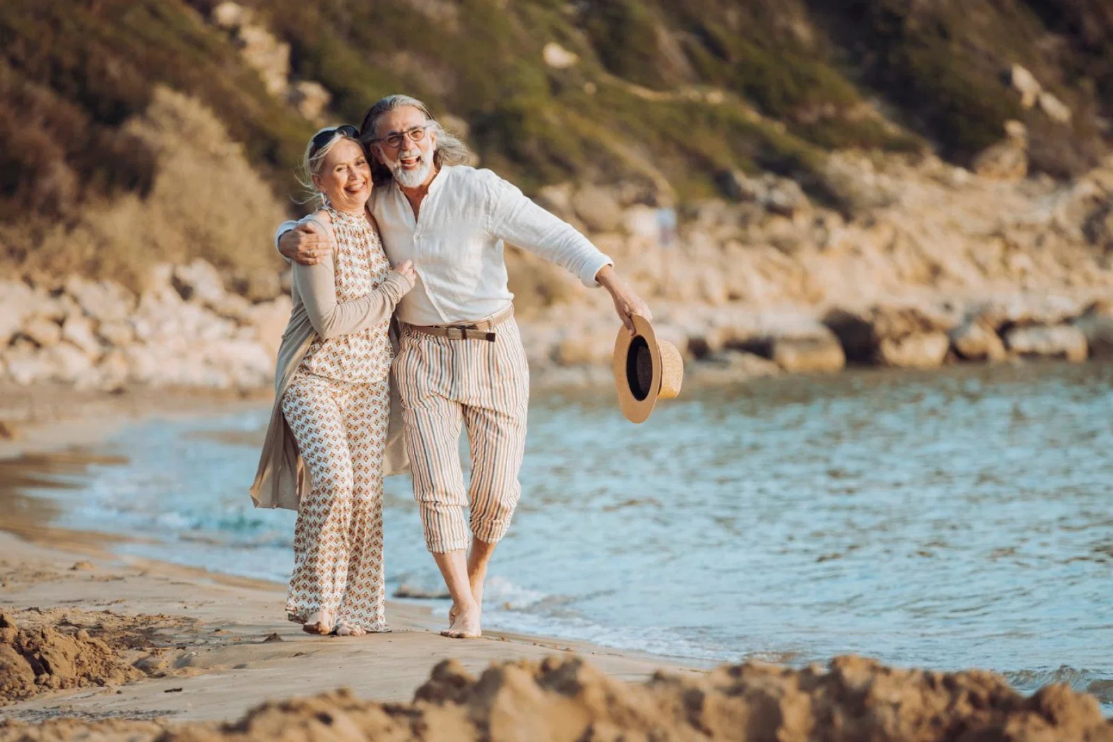 An older couple walk along the beach on holiday