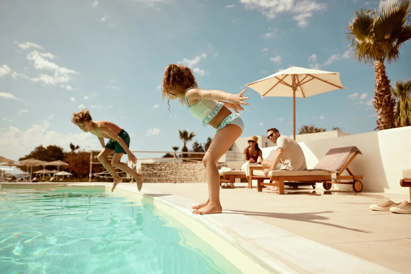 Two children mid-air jumping into a swimming pool 