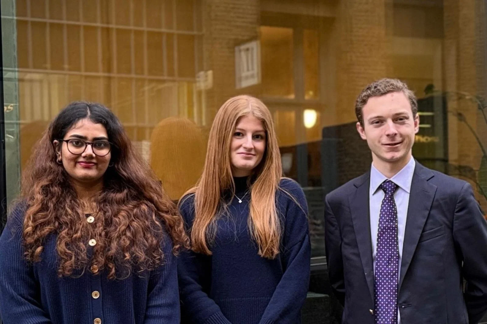 Three young people, two women and one man, dressed smartly 