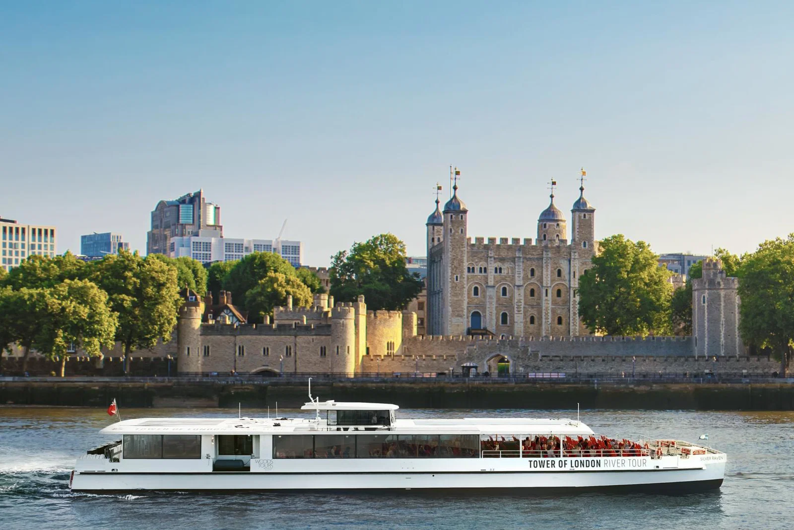 Serene view of the Silver Raven, the UK’s first electric tour boat, sailing the Thames toward Tower Bridge with the Tower of London behind