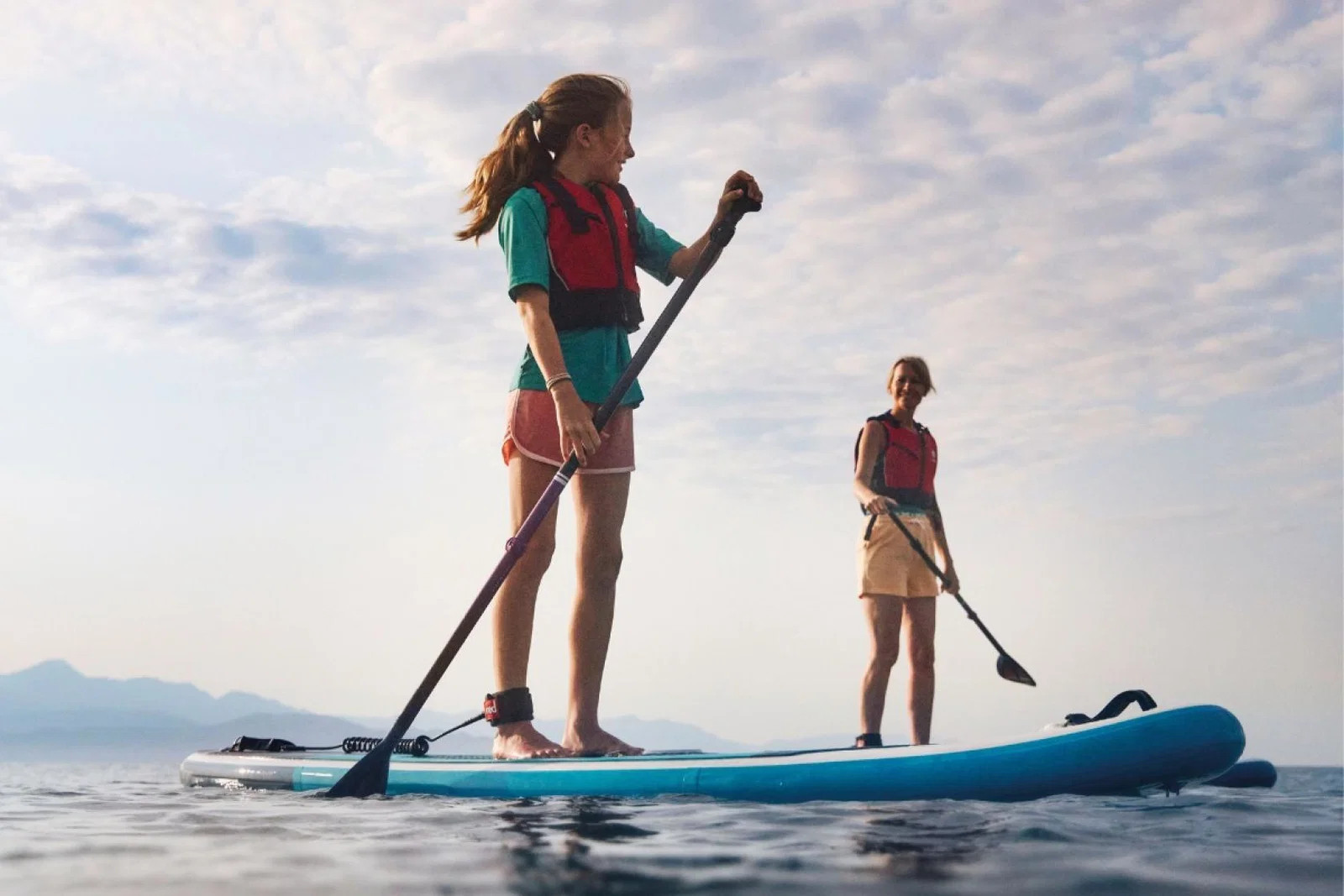 Two people standing on paddleboards 