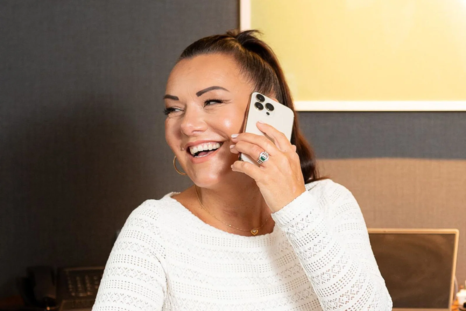 Brown haired woman smiling, she is on the phone 
