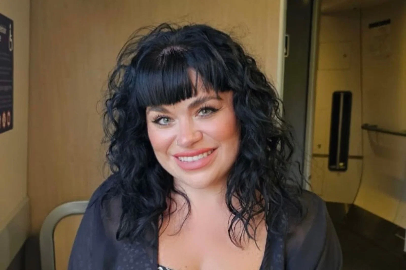 White woman with black curly hair smiling 