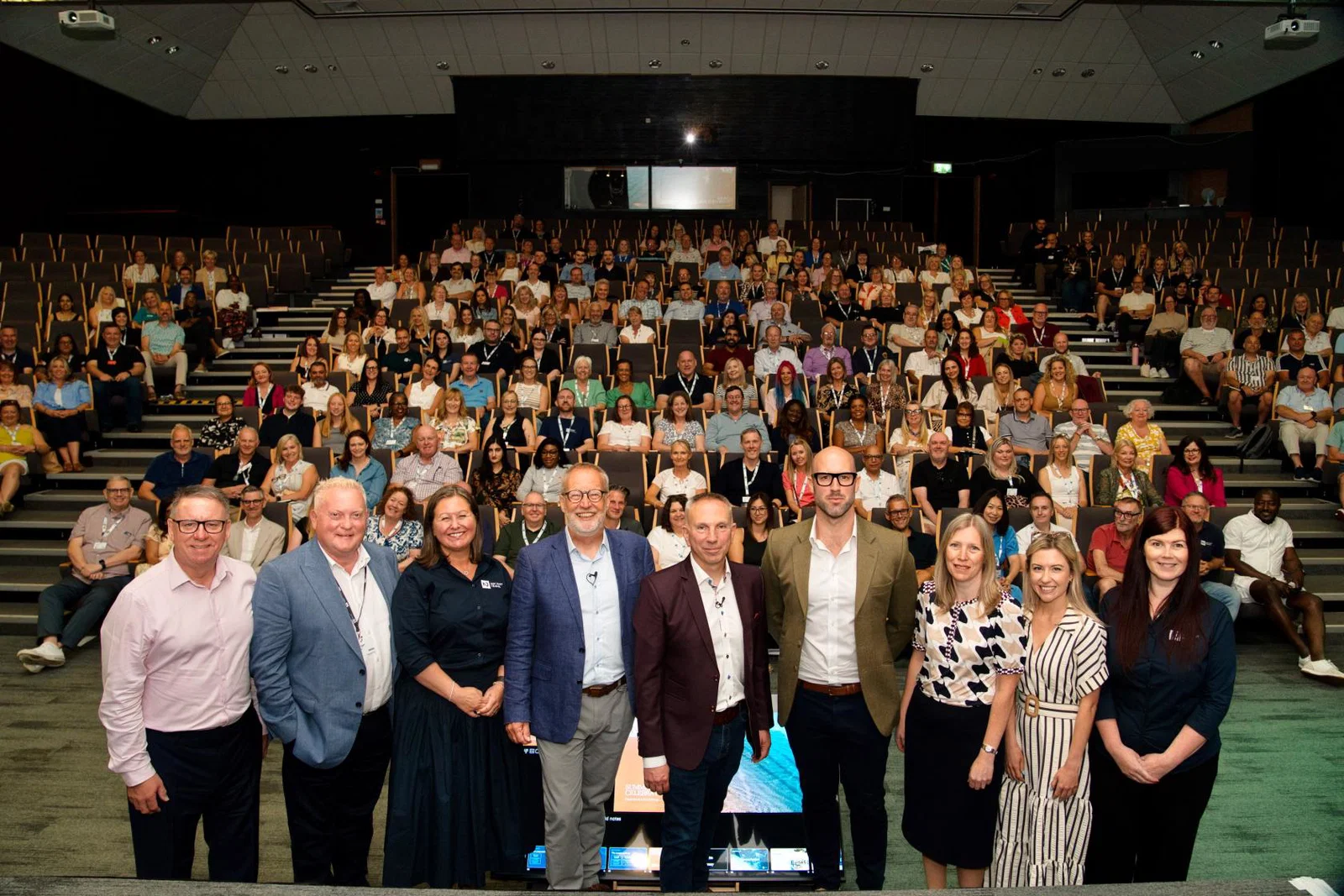 Not Just Travel co-founder Steve Witt and corporate team in front of an auditorium full of travel consultants