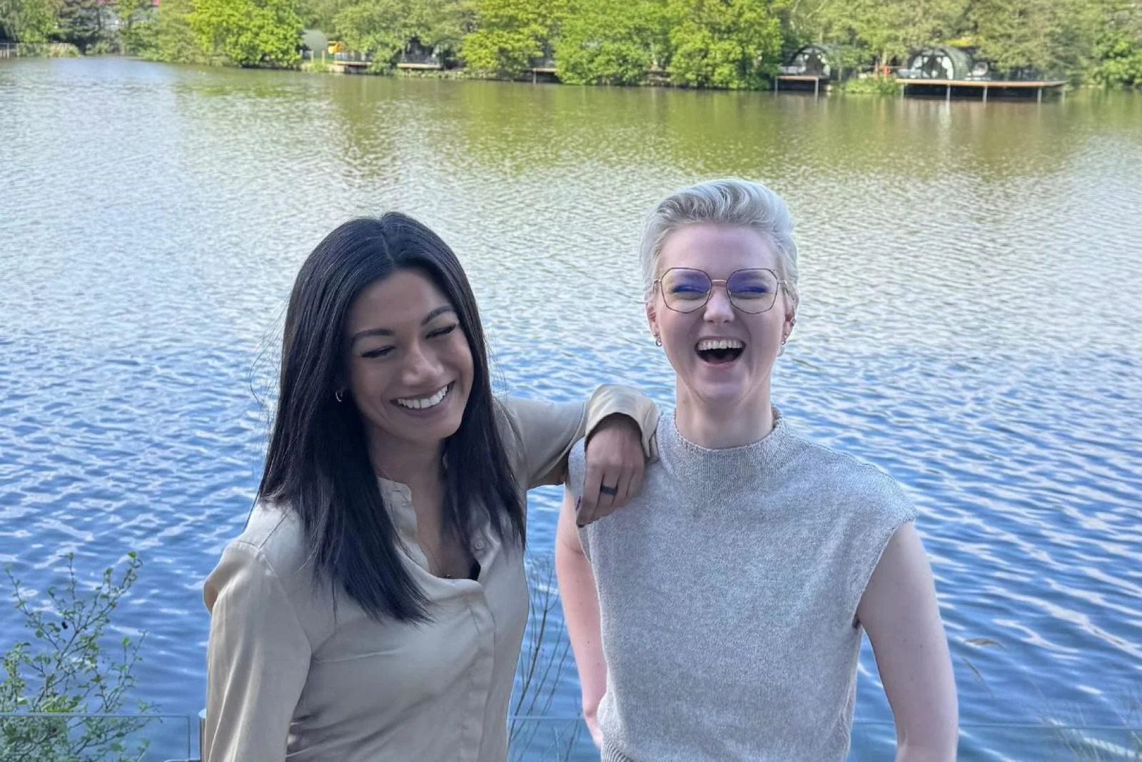 Two women smiling in front of water 