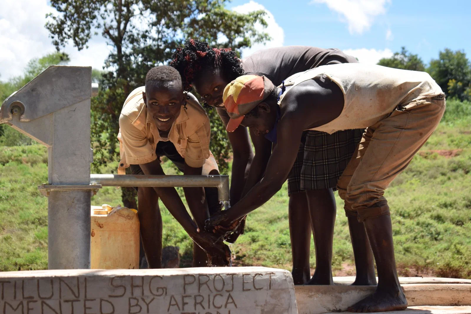 Children collect water from a sand dam pump in Kenya