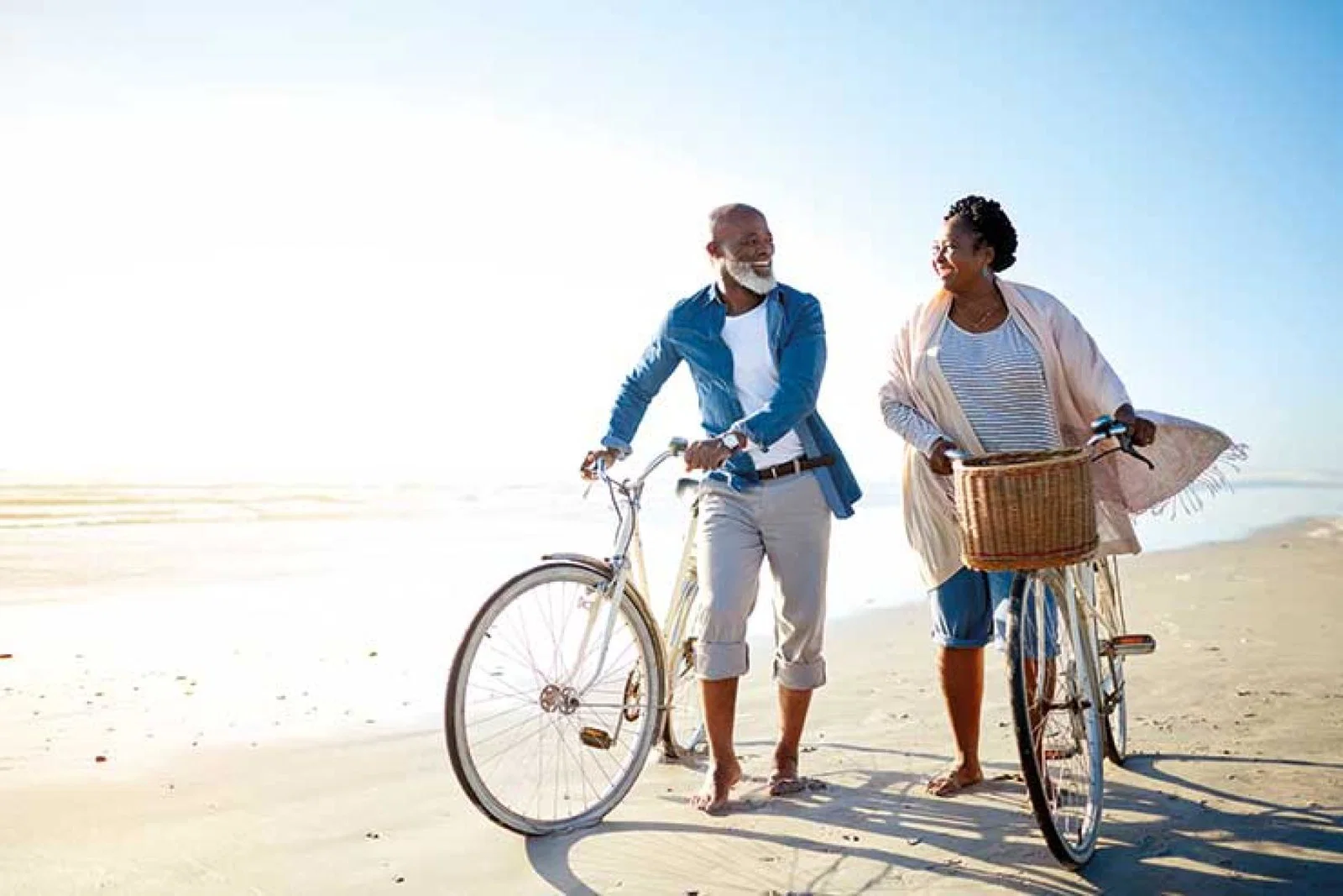 Over-50s couple with bicycles on the beach