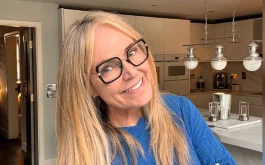 Woman smiling with blonde hair and glasses, her background is a modern kitchen