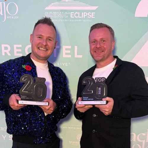 Two men holding trophies and smiling 