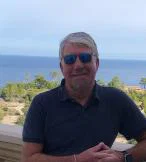 White man smiling in front of sea background