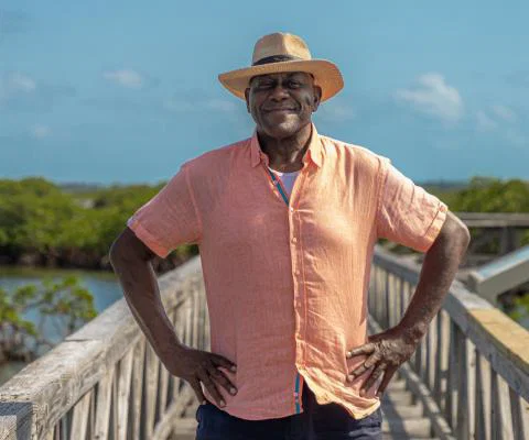 Ainsley Harriot standing with hands on hips on boardwalk over mangrove