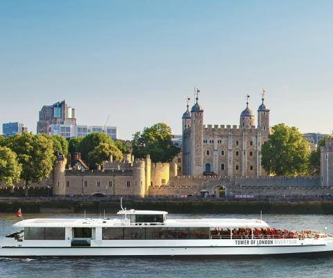 Serene view of the Silver Raven, the UK’s first electric tour boat, sailing the Thames toward Tower Bridge with the Tower of London behind