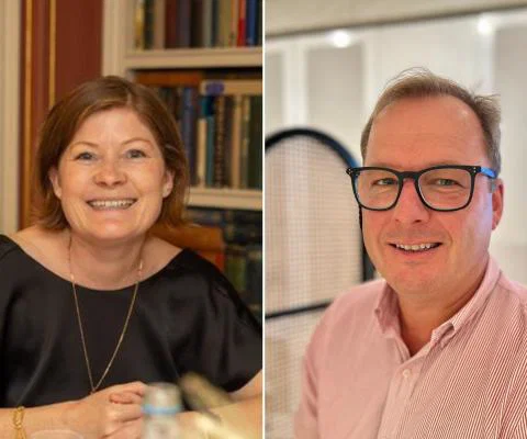 Woman with short brown hair smiling and man with glasses smiling 