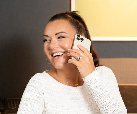 Brown haired woman smiling, she is on the phone 