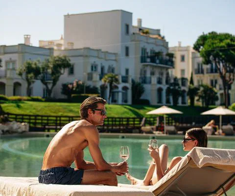 Man and woman sitting on sunchairs beside hotel pool