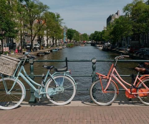 Bikes rest on hand rail with canal view in background in Amsterdam