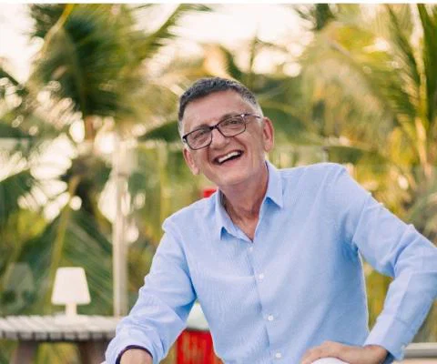 White man smiling with outdoors green background