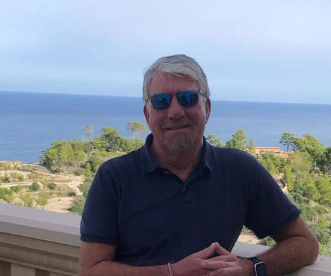 White man smiling in front of sea background