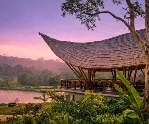 Curved roof villa terrace overlooking peaceful lake with pink sky 