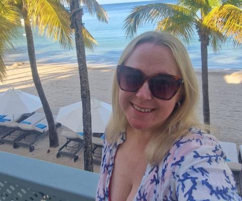 Blonde woman with sunglasses smiling in tropical location   