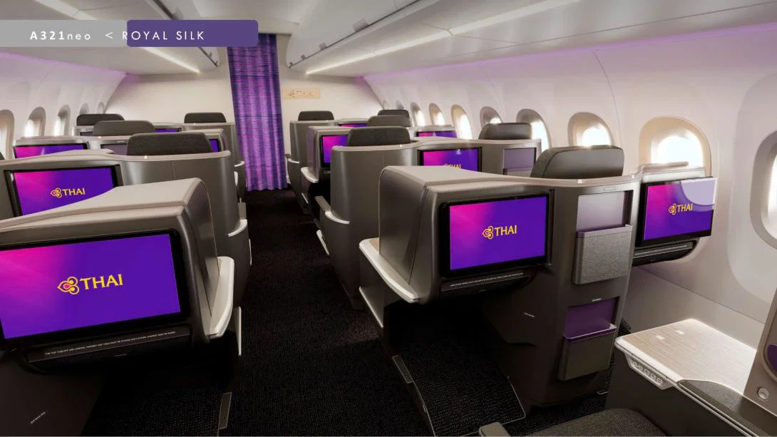 Buisness class seating on plane with TV screens and plane aisle
