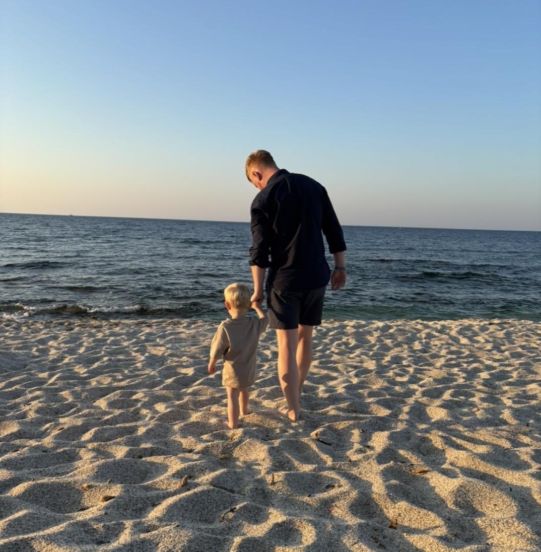Tom Parry holds his son's hand as they walk down the beach Tom Parry holds his son's hand as they walk down the beach