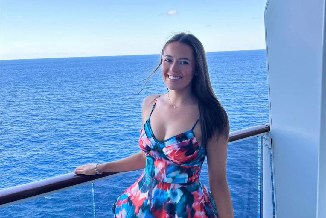 Young woman with brown hair smiling on ship balcony with sea background