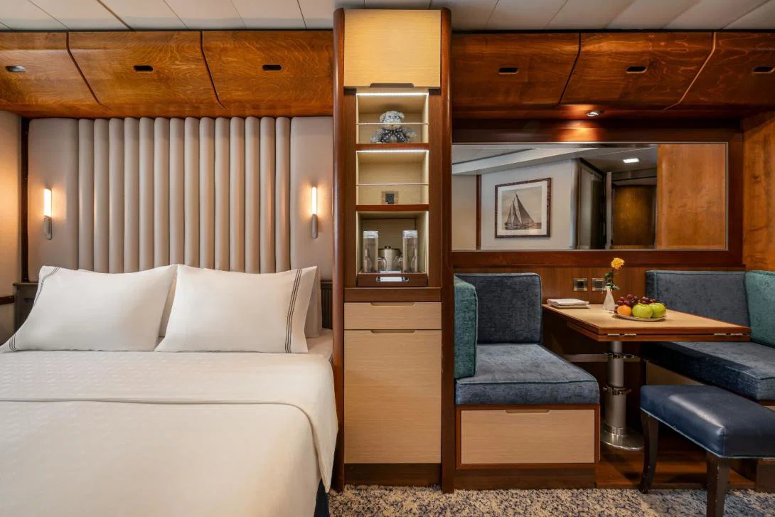 Luxury cruise cabin with white sheeted bed warm interiors