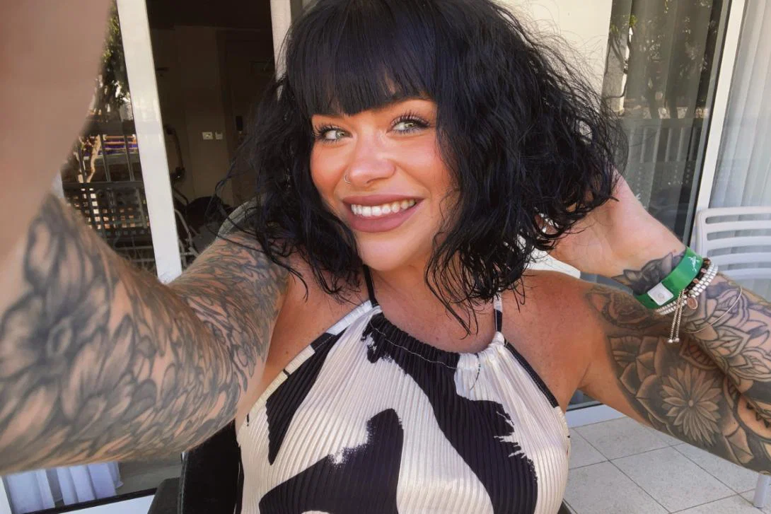 Smiling white woman with black hair, red lipstick and tattoos