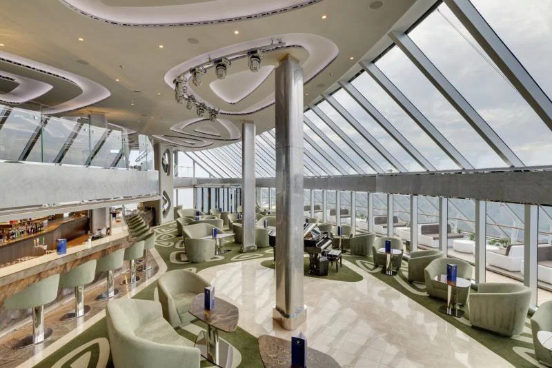 View of cruise ship lounge and bar area with large windows out to sea
