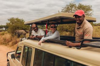 Two people in a safari jeep with an Intrepid guide